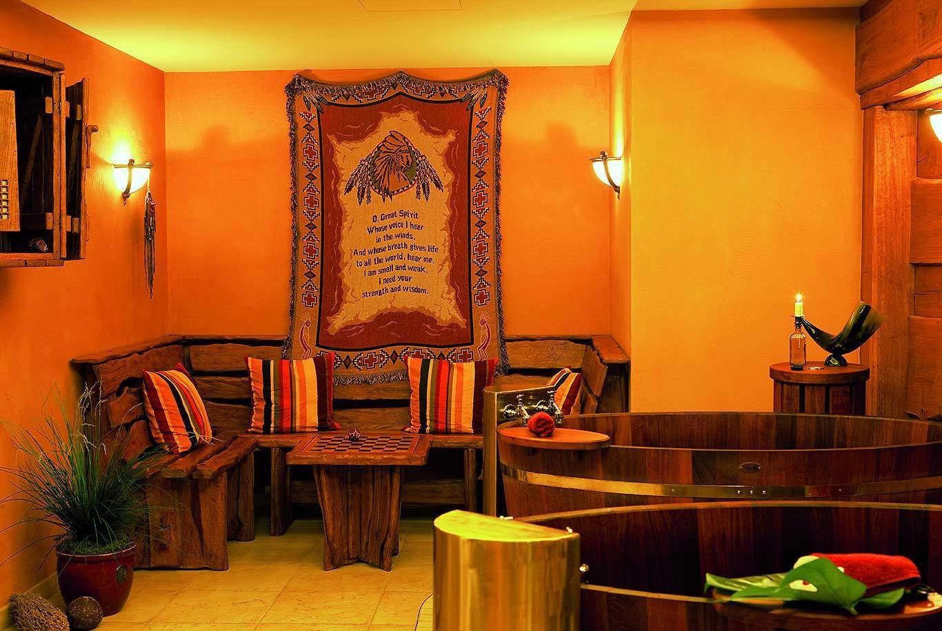 A cozy room with a wooden bench, a small table, and a wall hanging with a Native American design.