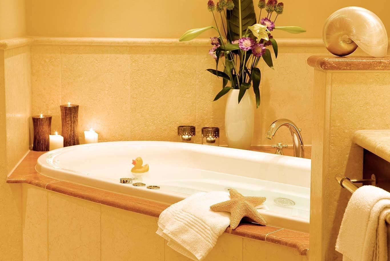 A bathroom with a bathtub, a starfish decoration, a rubber duck, and a vase with flowers.