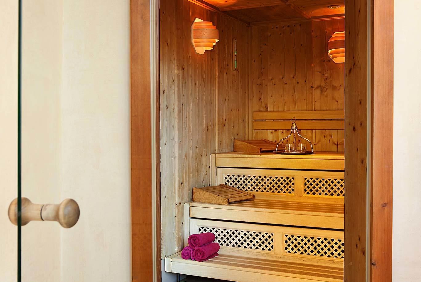 A wooden sauna with a bench, a tray with a candle, and a rolled-up towel.