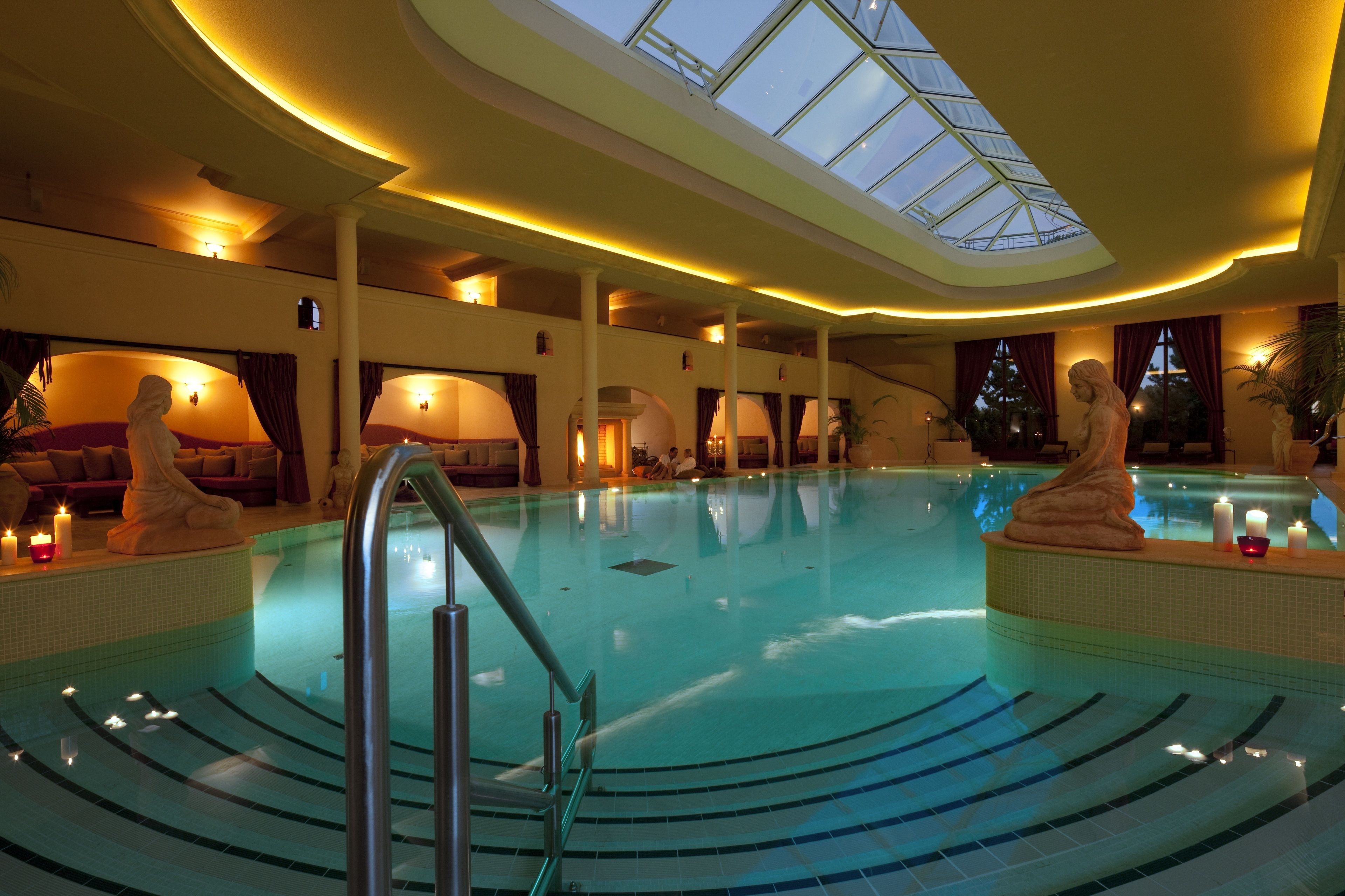 Una piscina interior con tragaluces, una zona de estar hundida y una estatua.