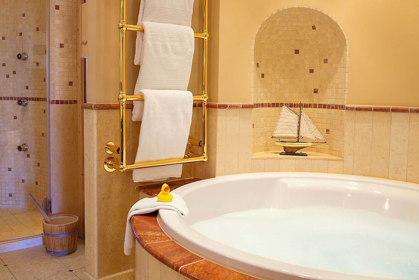 A bathroom with a bathtub, a shower, and a towel rack with multiple towels.