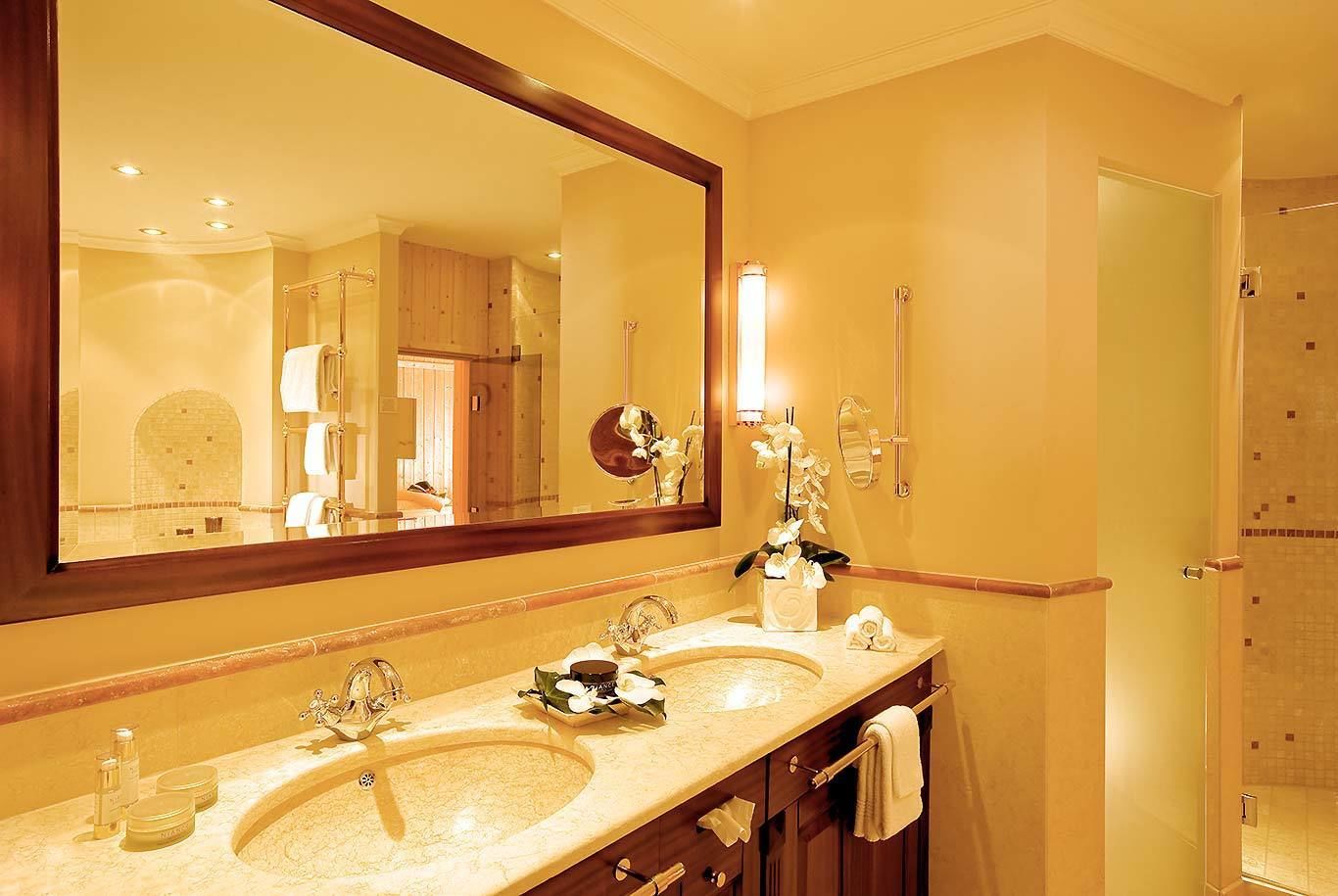 A hotel bathroom with two sinks, a large mirror, and a shower area.