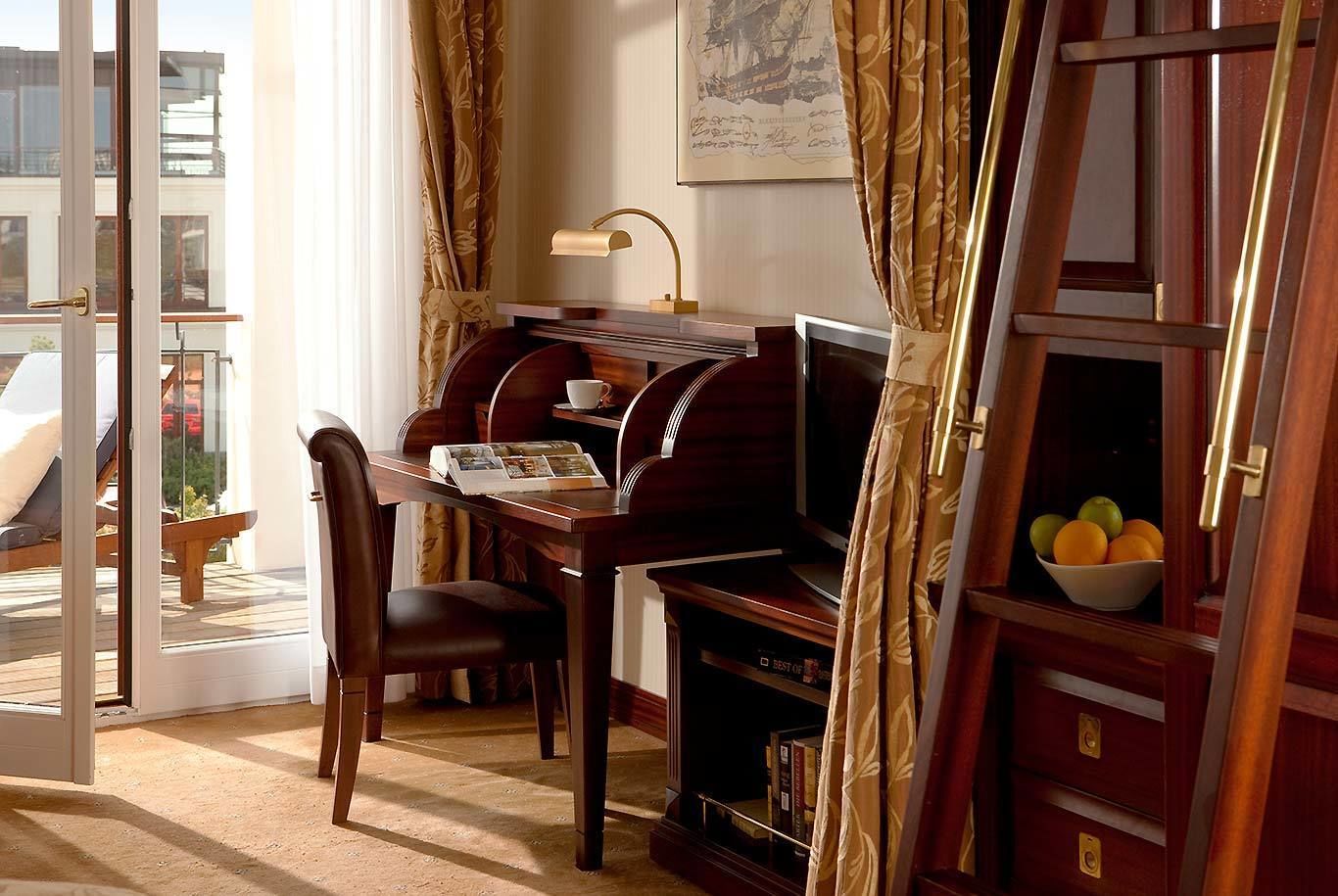 A room with a wooden desk, a television, and a bookshelf.