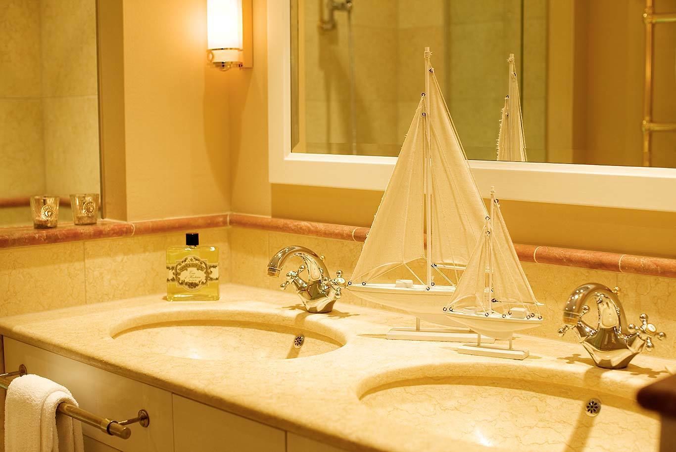 Un baño con dos lavamanos, un espejo y un modelo decorativo de un velero.