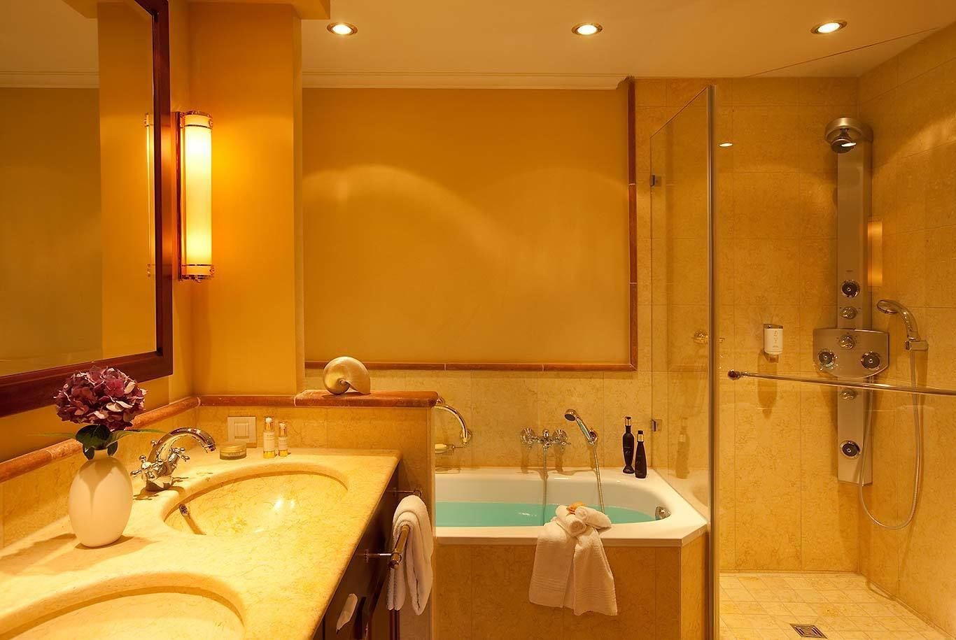 A bathroom with a double sink, a bathtub, and a walk-in shower.