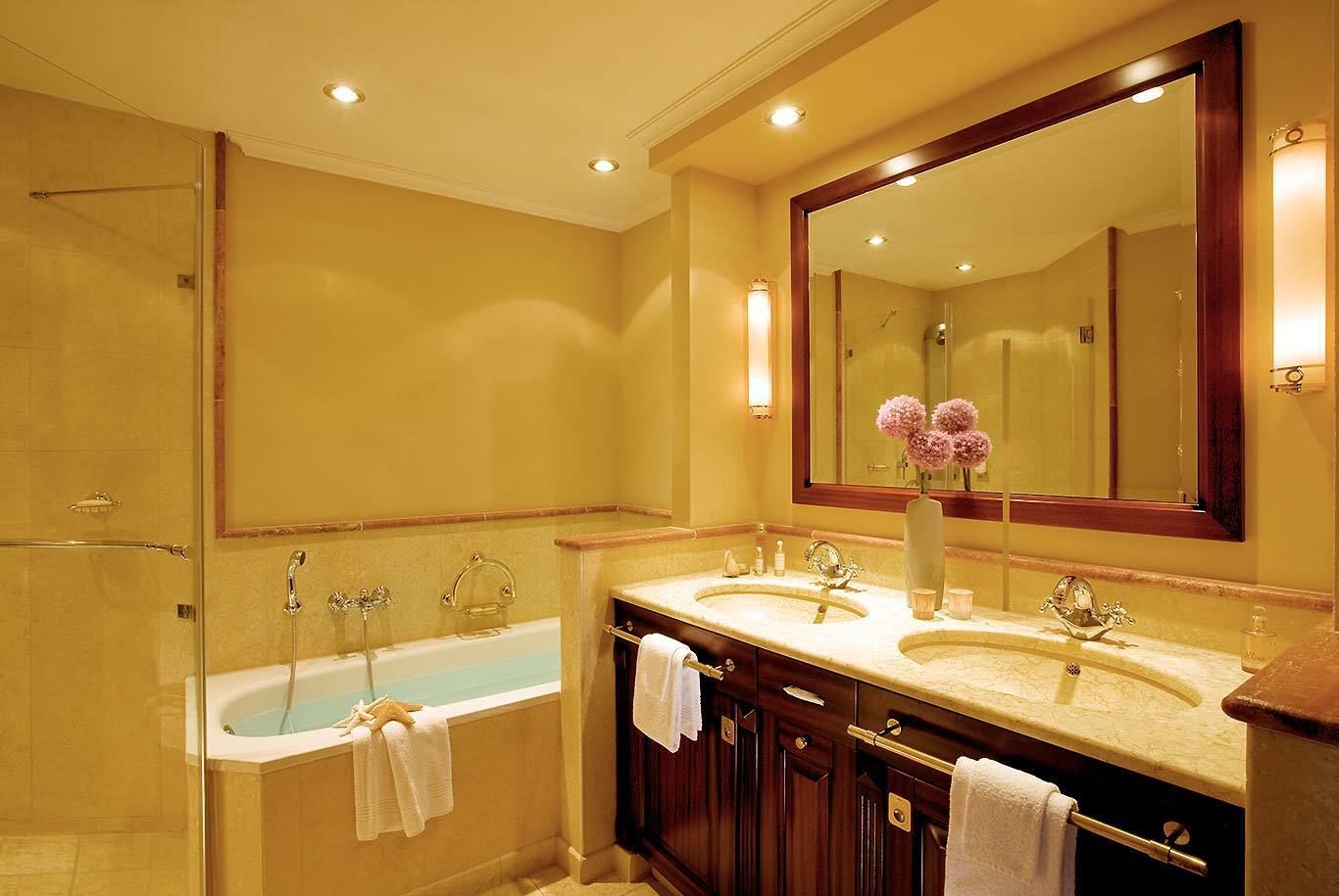 Un baño con bañera, dos lavamanos, un espejo grande y zona de ducha.