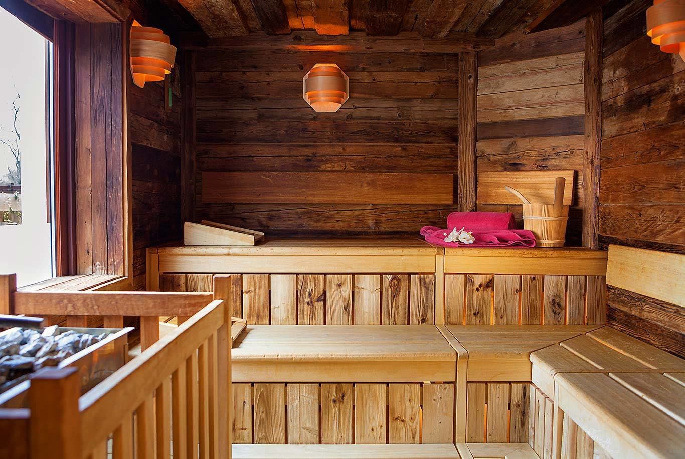 Una sauna de madera con bancos y un asiento integrado, pared de madera y ventana.