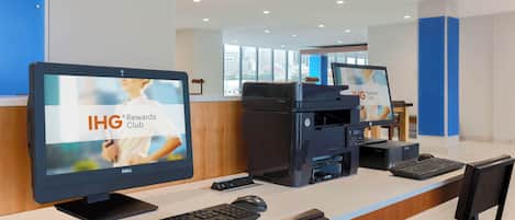 A reception desk with a computer monitor displaying 'IHG Rewards Club,' a printer, a keyboard, and a mouse.