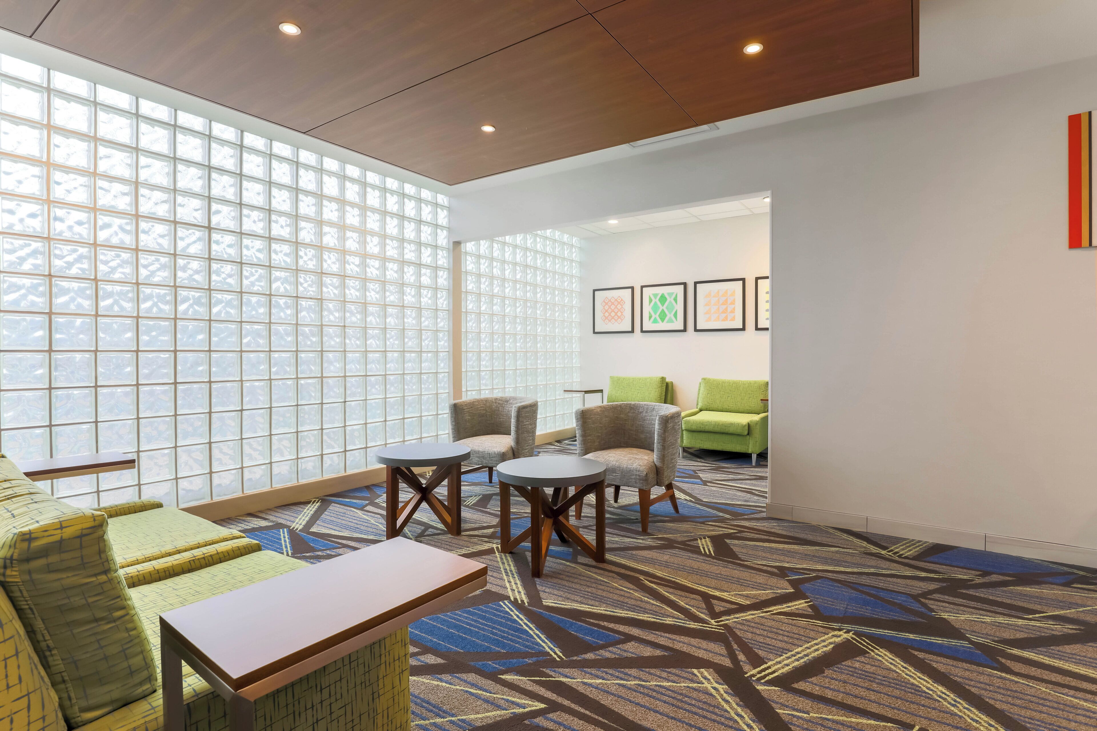 Un hall d’hôtel avec un espace salon, une moquette à motifs et des œuvres d’art accrochées au mur.
