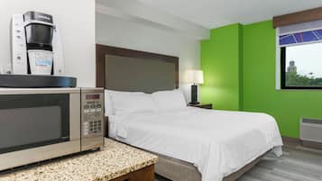 A hotel room with a bed, a coffee maker, a lamp, and a window with a view.