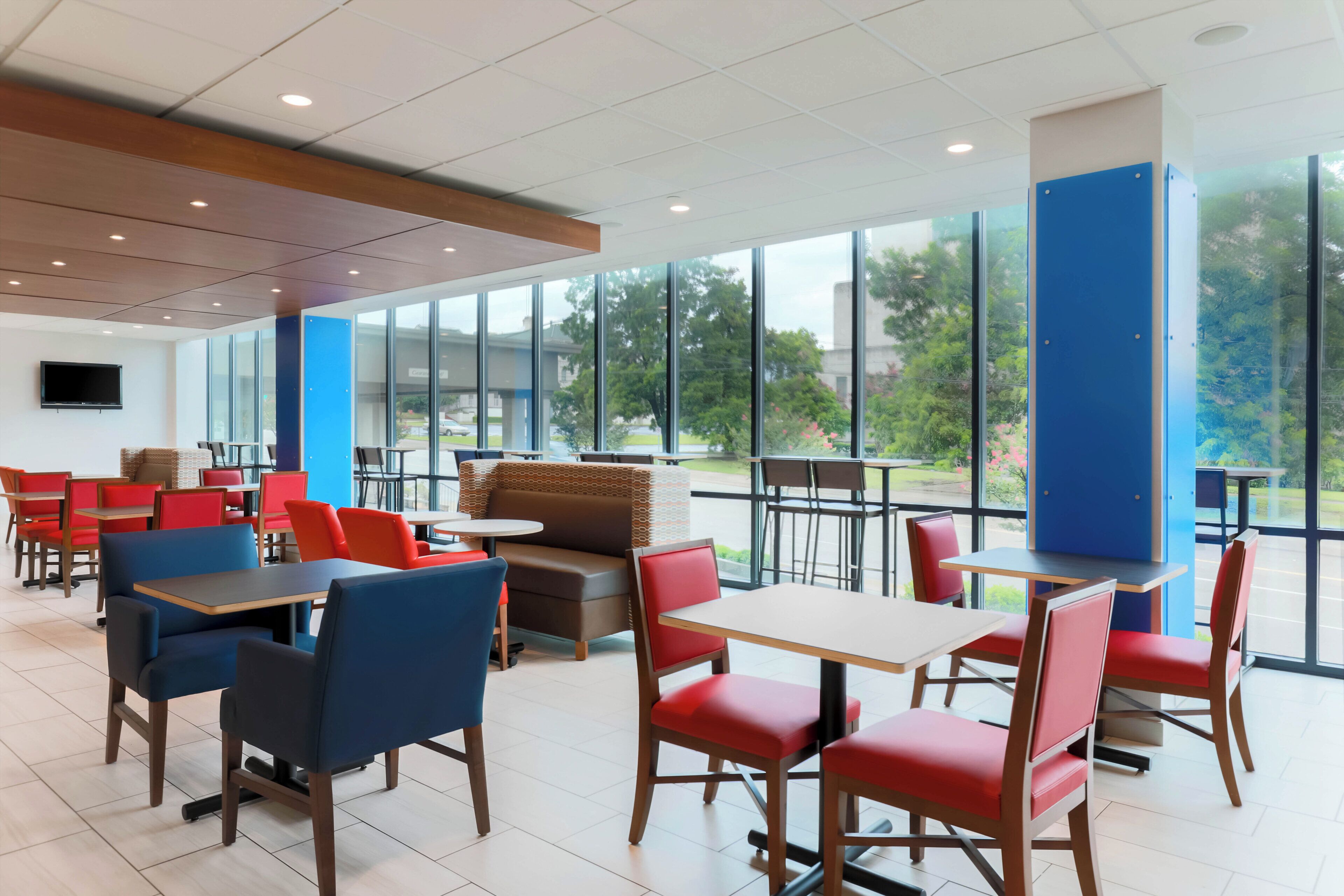 Un comedor moderno con mesas y sillas, ventanas amplias y vistas al exterior.