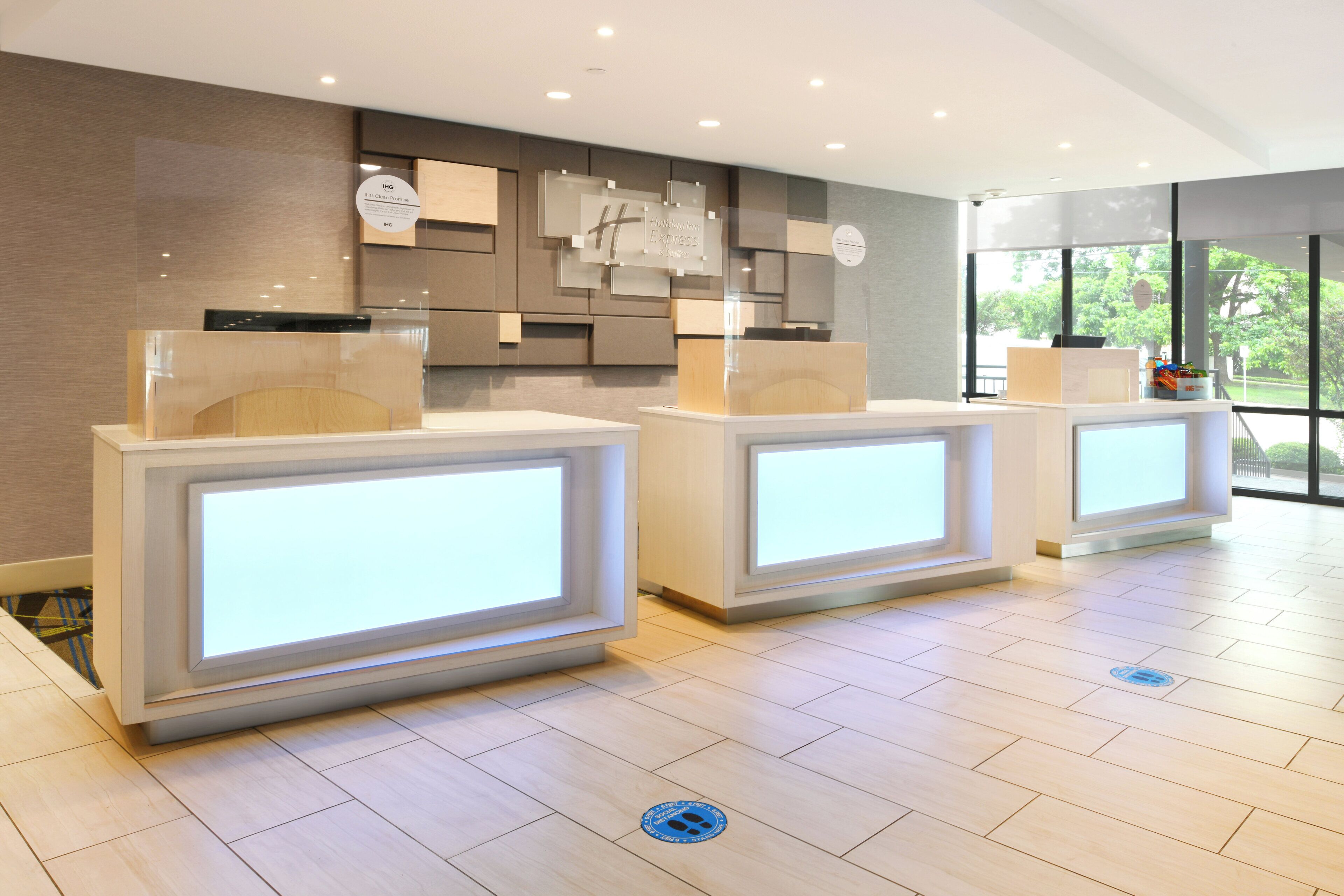 A reception area with three reception desks, a modern design, and a view of the outdoors through large windows.
