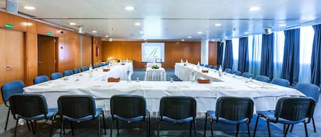 Un salón de conferencias con una larga mesa, sillas azules y una pantalla proyectora mostrando 'HOTEL AFRICA'.