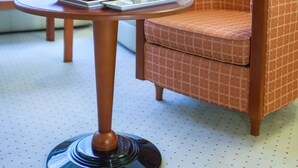 Una habitación de hotel con una mesa redonda, una silla, una lámpara y una bandeja de frutas.
