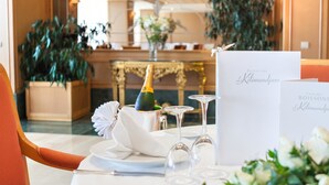 Una mesa lista para una comida, con una botella de champán, copas y una carta.