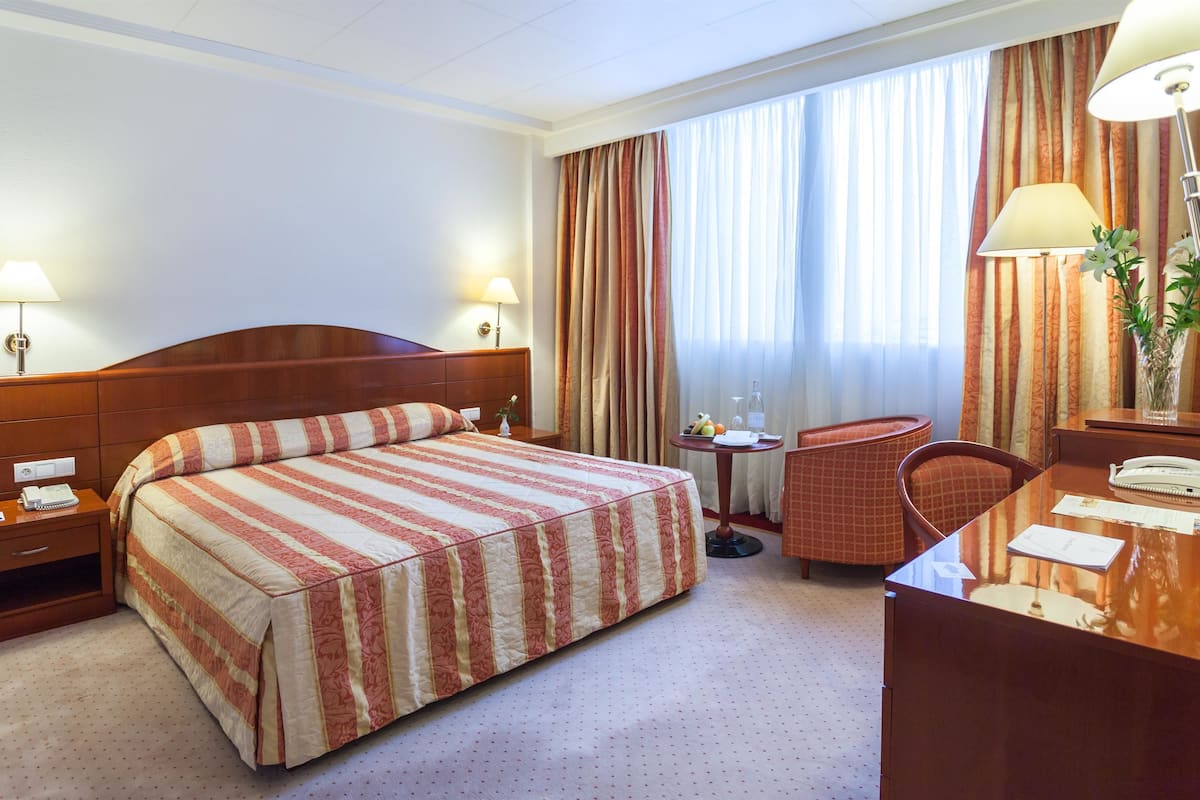 Una habitación de hotel con una cama grande, un escritorio, una silla y una mesita.