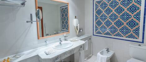 Un baño con tocador de mármol, un espejo grande, inodoro y bidé.