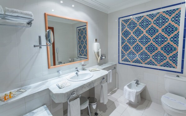 A bathroom with a marble vanity, a large mirror, a toilet, and a bidet. - Hotel Africa (Tunis)