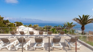 A terrace with sun loungers and a view of the sea.