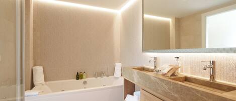 Un baño moderno con bañera, dos lavamanos y un espejo grande.