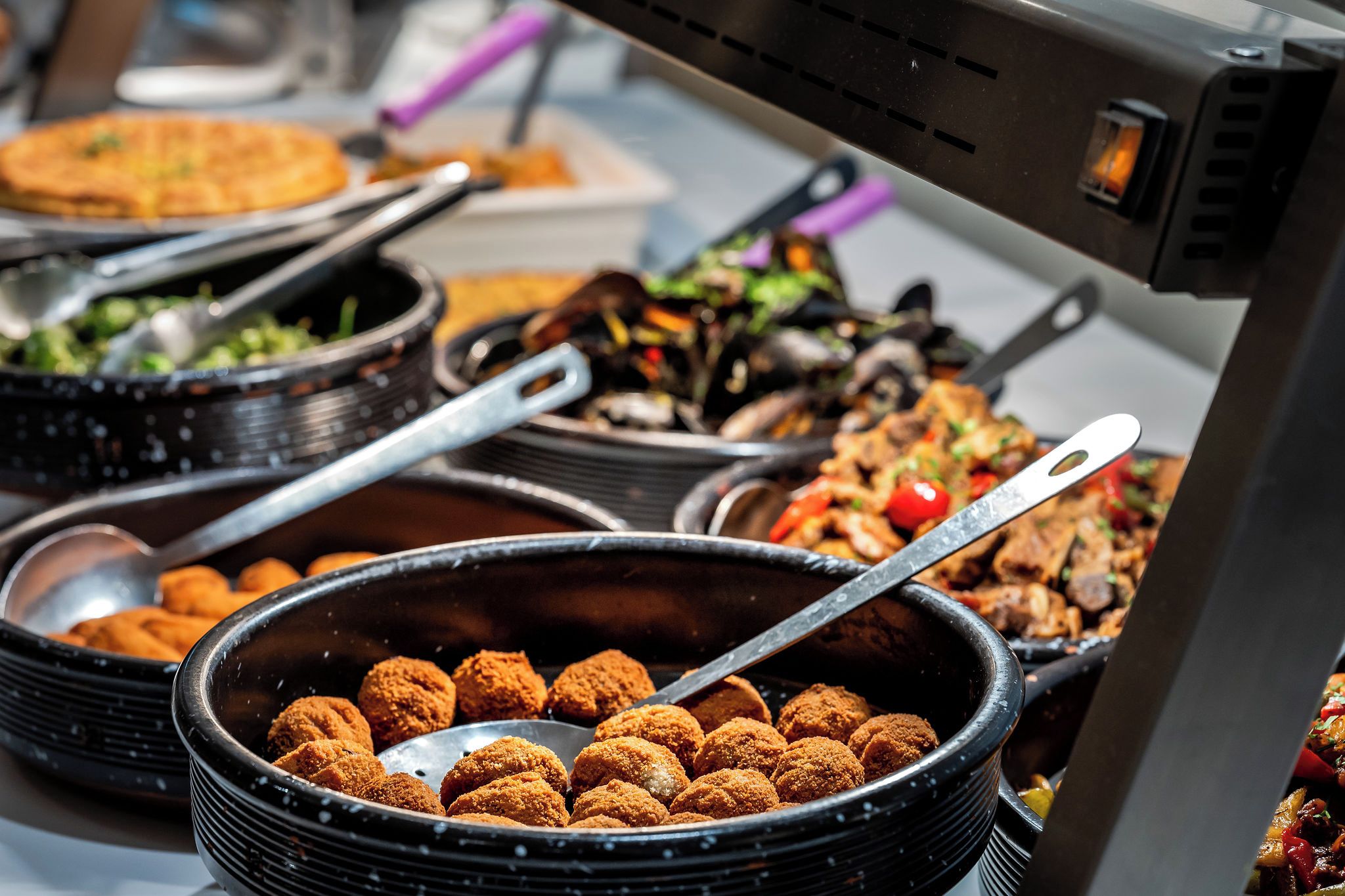 Ein Buffet mit verschiedenen Speisen, darunter eine Schüssel mit panierten Artikeln, ein Salat und eine Gemüsepfanne.