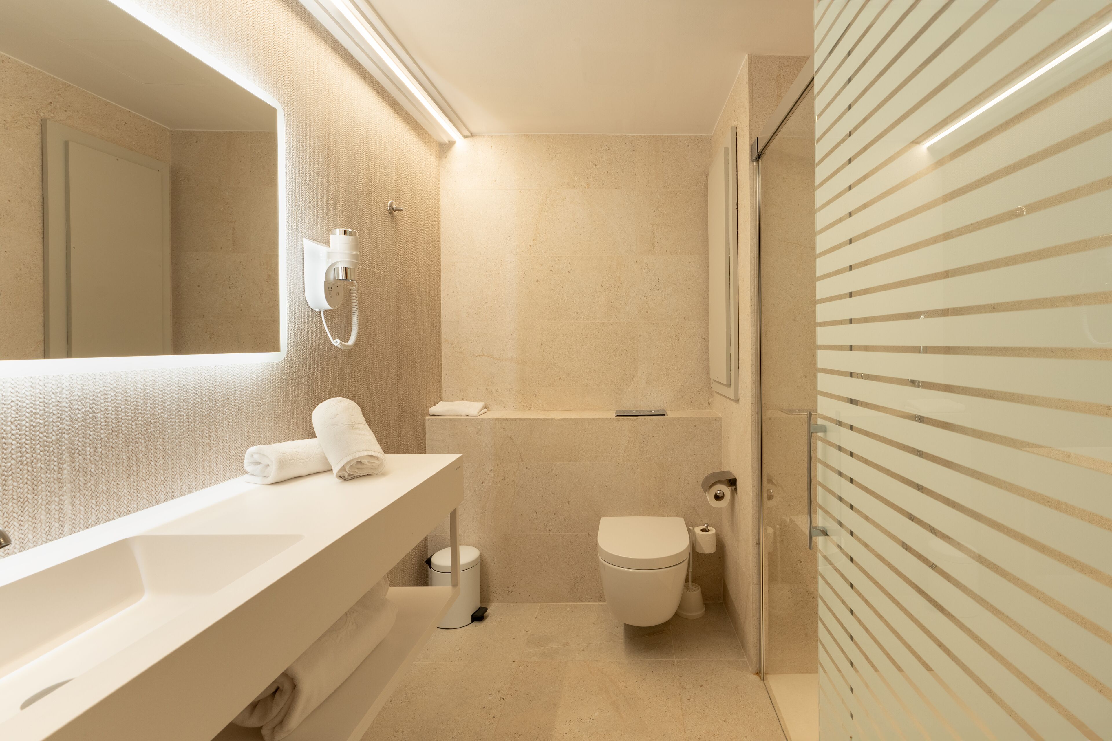 A modern bathroom with a large mirror, a sink, a toilet, and a shower area.