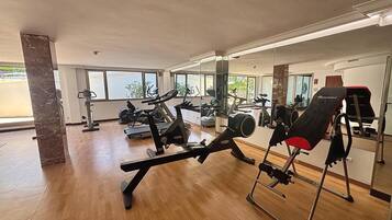 A gym with cardio machines, weightlifting equipment, and mirrors on the walls.