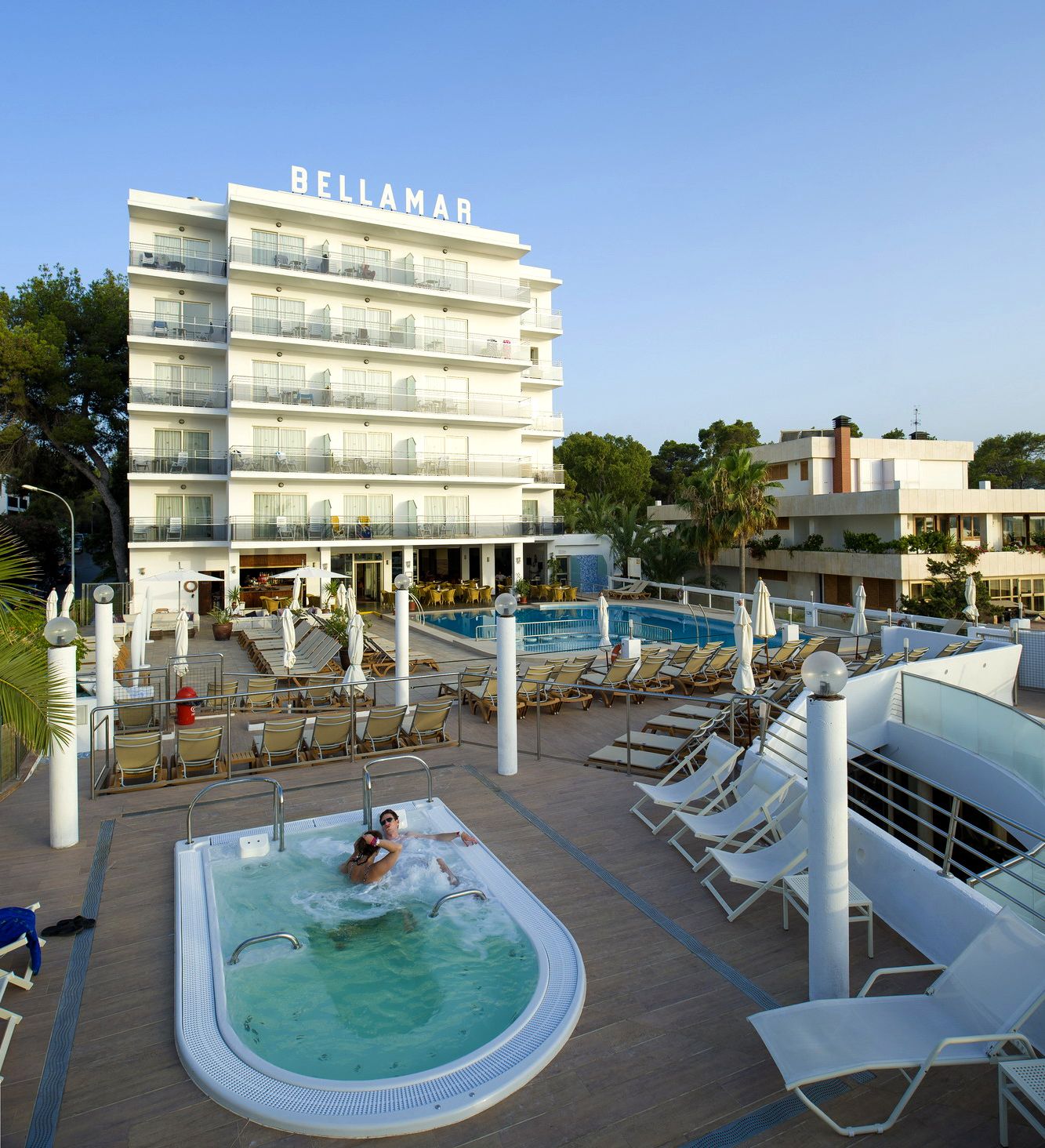 A hotel named 'BELLAMAR' with a pool area, sun loungers, and a bar/lounge area.