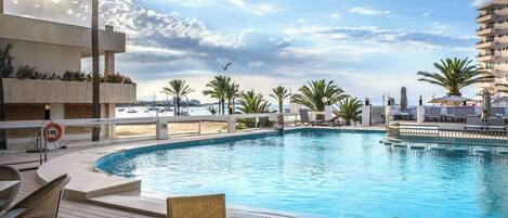 Un área de piscina con sillas de descanso y vista al mar.