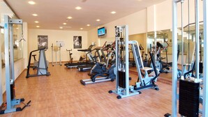 A gym with various exercise machines, a television, and a tiled floor.