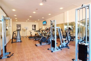 A gym with various exercise machines, a television, and a tiled floor. - Zafiro Mallorca (Santa Margalida)