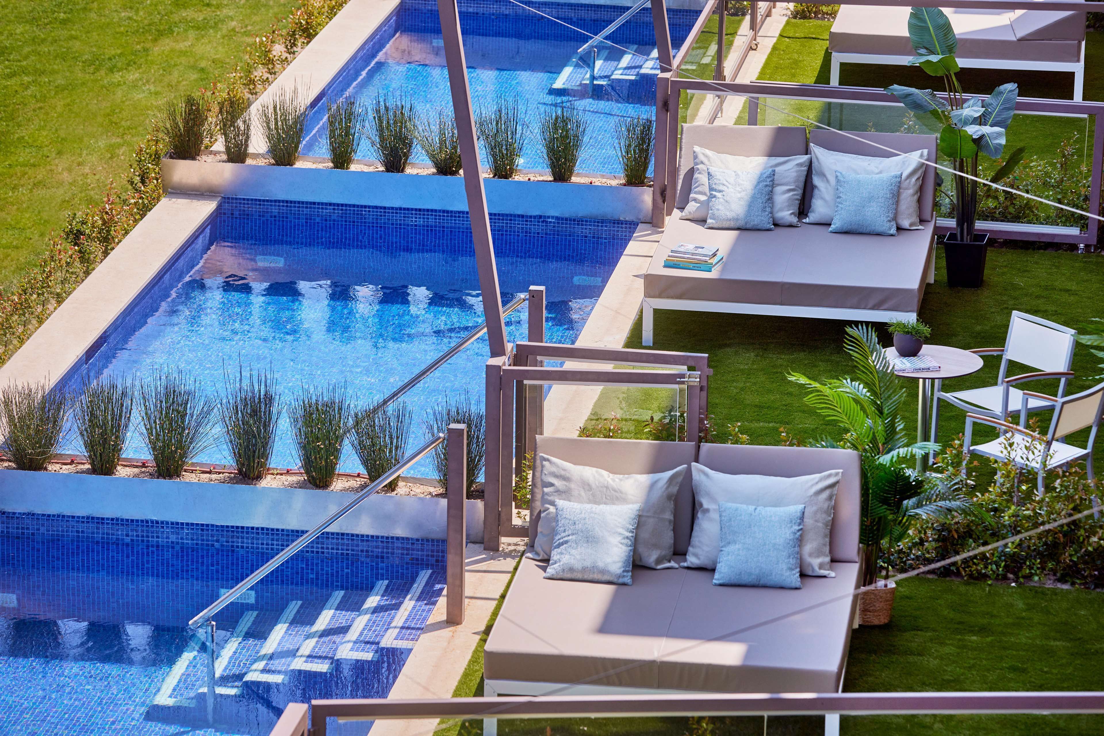 A rooftop pool area with multiple seating areas and a glass balustrade.
