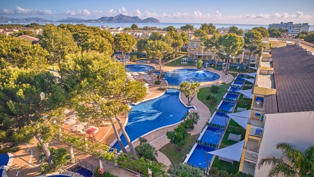 A resort with multiple swimming pools, lush greenery, and a view of the sea.