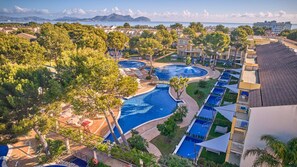 Ein Resort mit mehreren Schwimmbecken, üppiger Vegetation und Meerblick.
