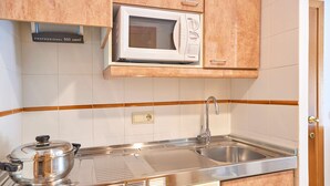 A kitchen with a microwave, stove, sink, and wooden cabinets.