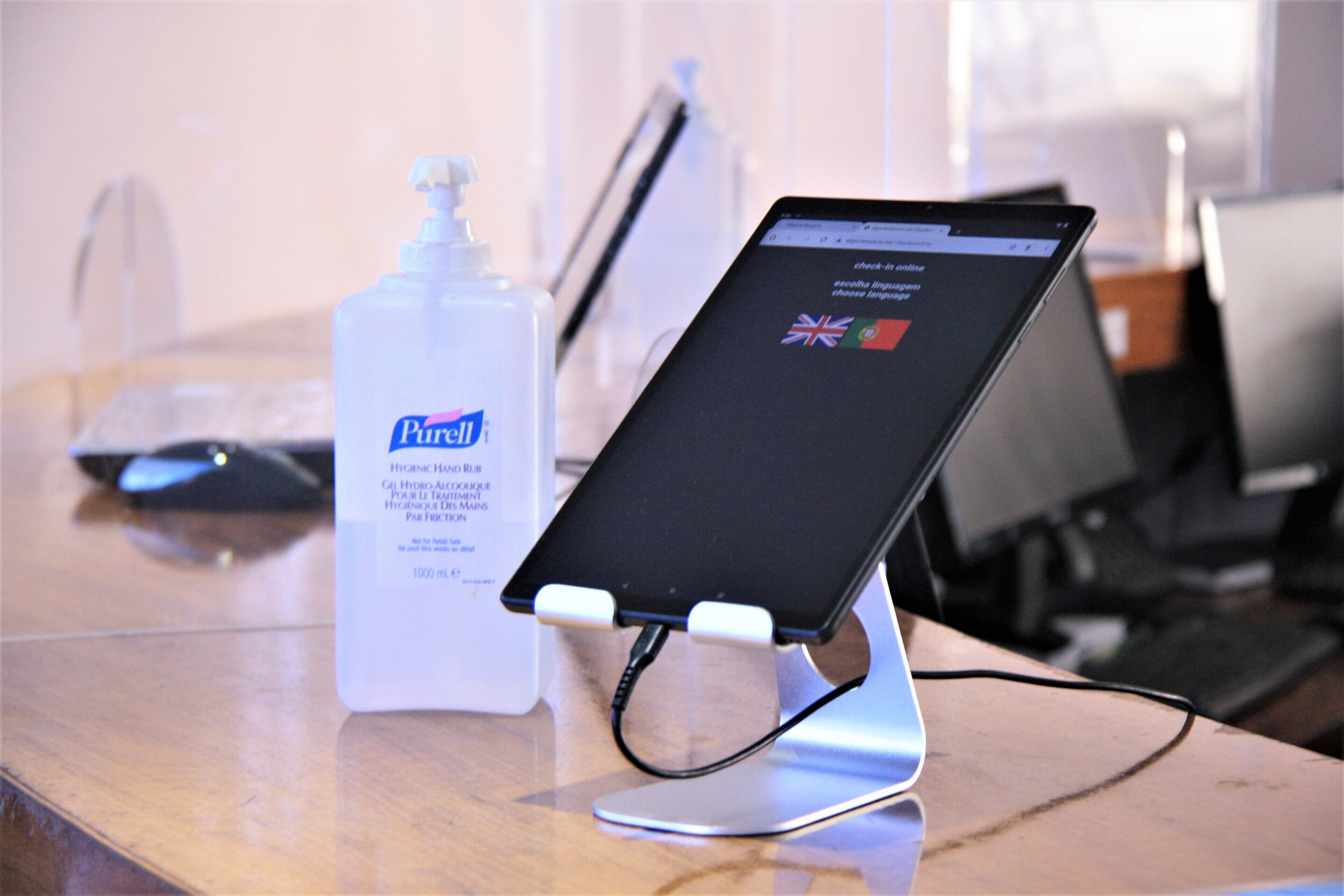 A tablet on a stand with a bottle of Purell hand sanitizer nearby.