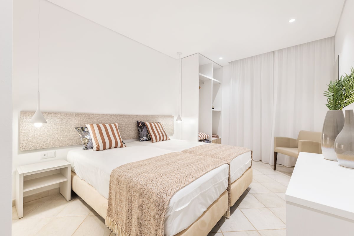 A modern bedroom with a large bed, bedside tables, a desk, and a chair.