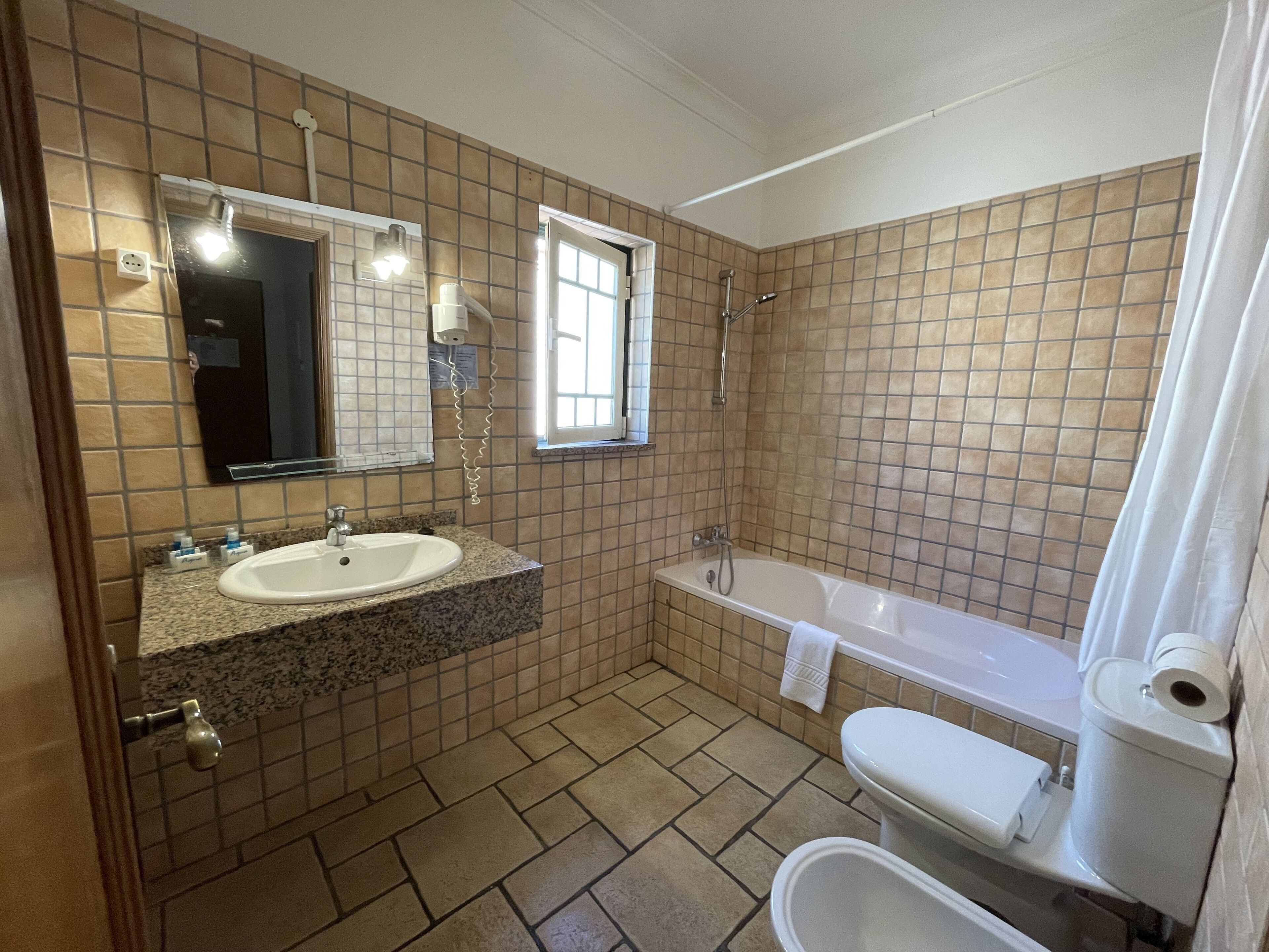 Ein Badezimmer mit Waschbecken, Spiegel, Dusche und Toilette.