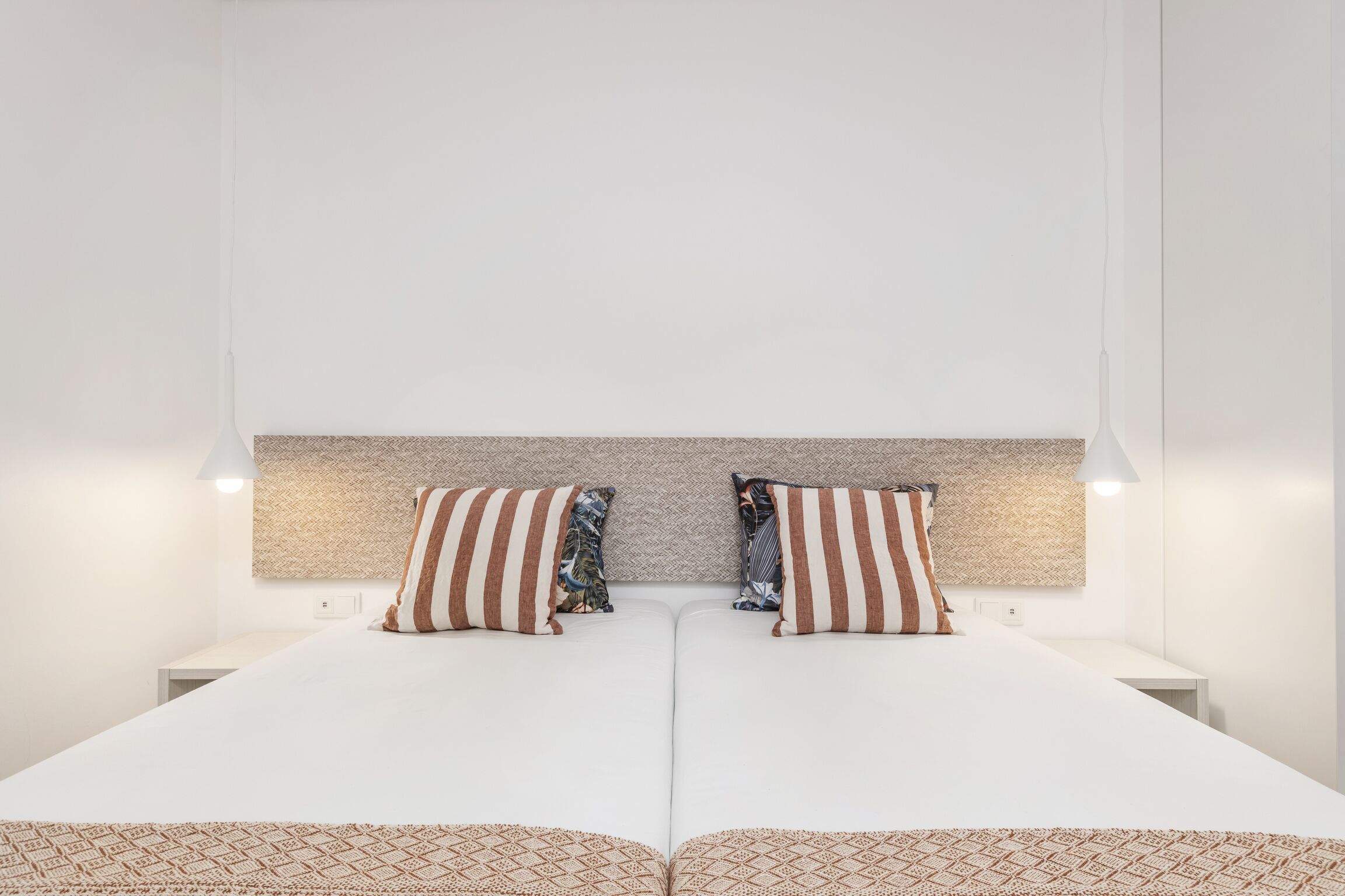 Una camera d'albergo moderna con un letto grande, due comodini e una testiera dal design strutturato.