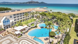 Un resort con una gran piscina, palmeras y vistas al océano.