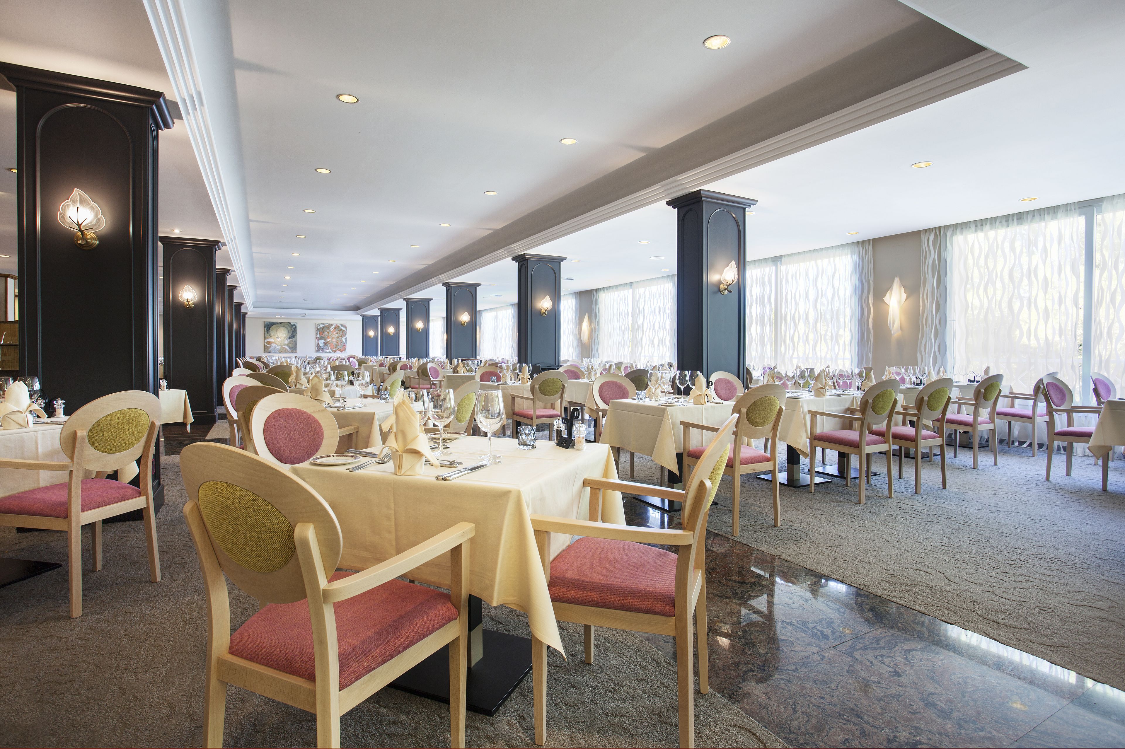 Een ruime balzaal met meerdere ronde tafels, elk voorzien van stoelen en gedekte plaatsen.