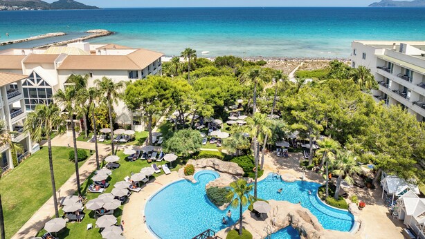 Un resort con una gran piscina, palmeras y vista al océano.