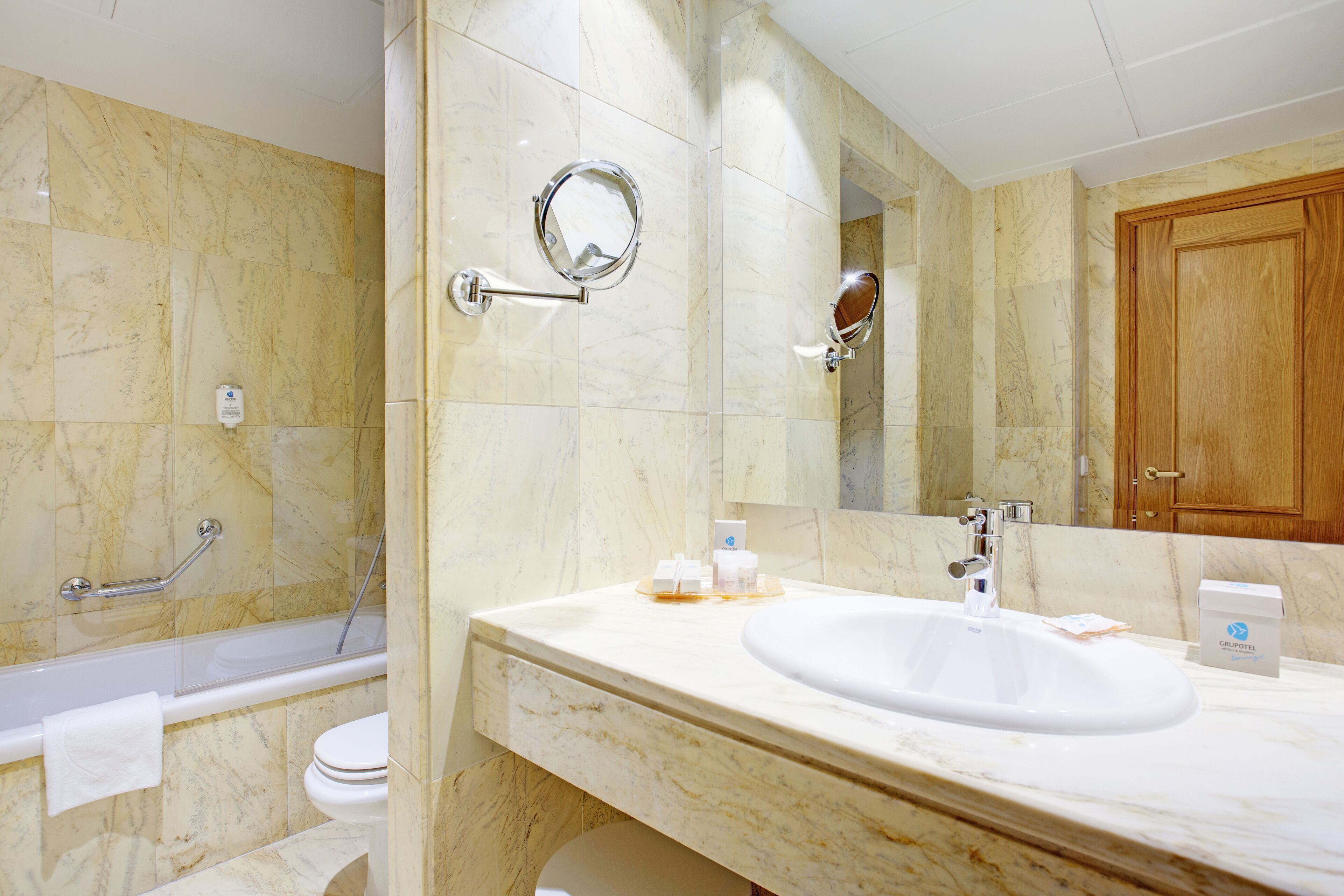 Un baño con lavamanos de mármol, bañera, inodoro y espejo.
