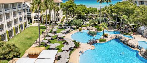 A resort with a large pool, palm trees, and a view of the ocean.