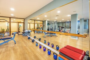 A gym with exercise equipment, a mirror, and a wooden floor.