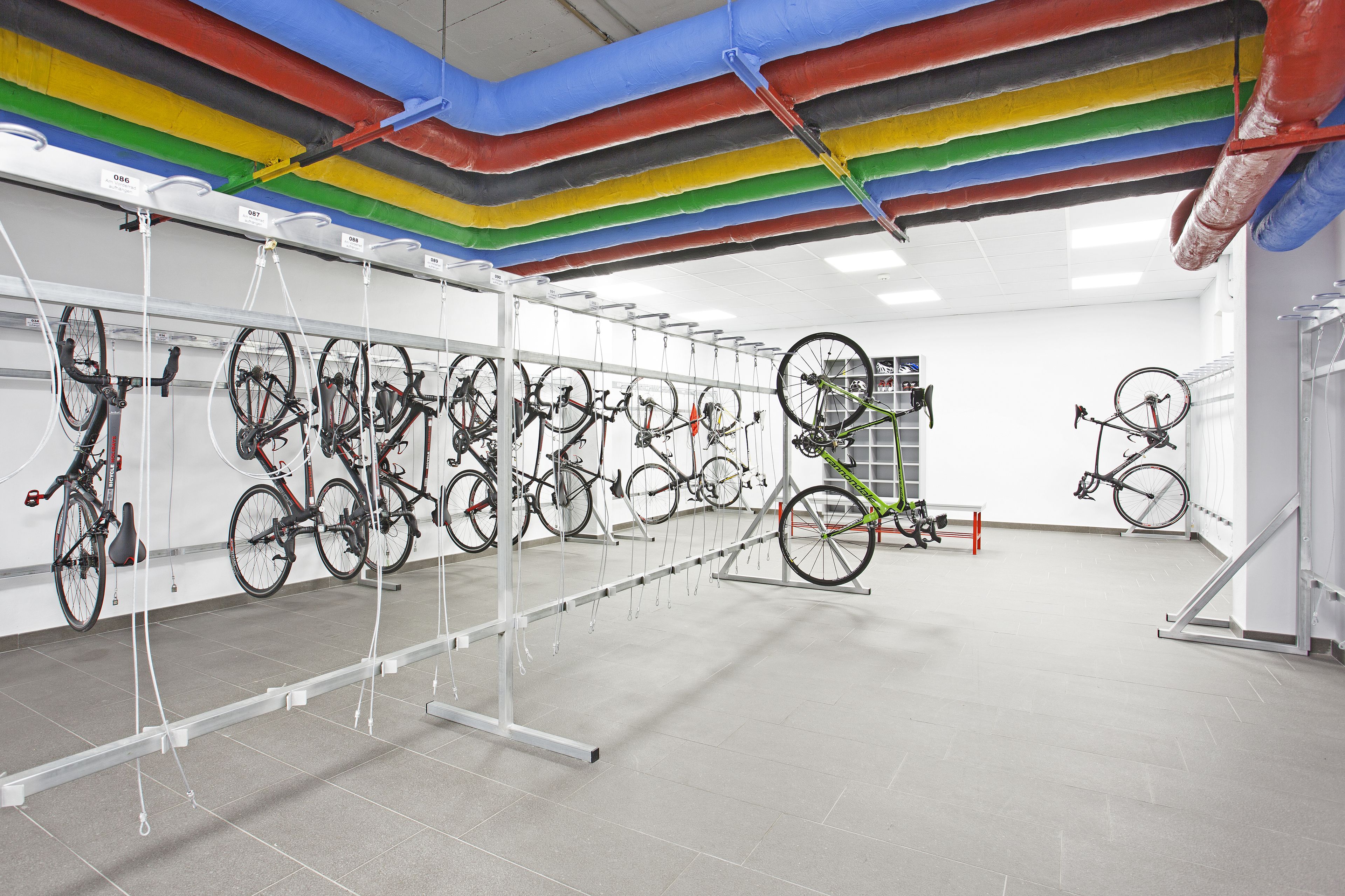A spacious indoor area with multiple bicycles mounted on racks against the walls.