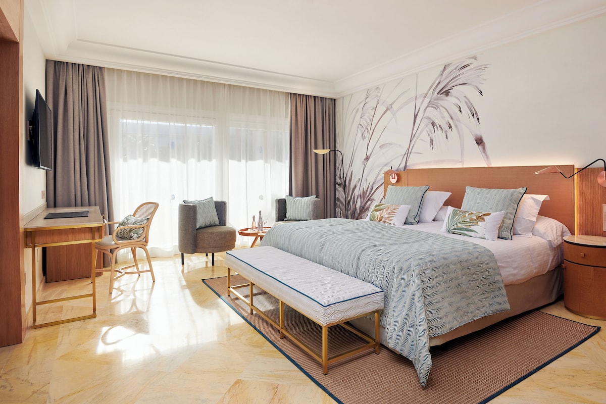 Ein modernes Hotelzimmer mit einem großen Bett, einem Schreibtisch, einem Sessel und einer Bank.