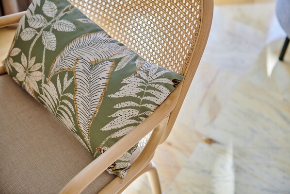 Une chaise dotée d’un dossier en osier et d’un coussin orné d’un motif de feuilles.