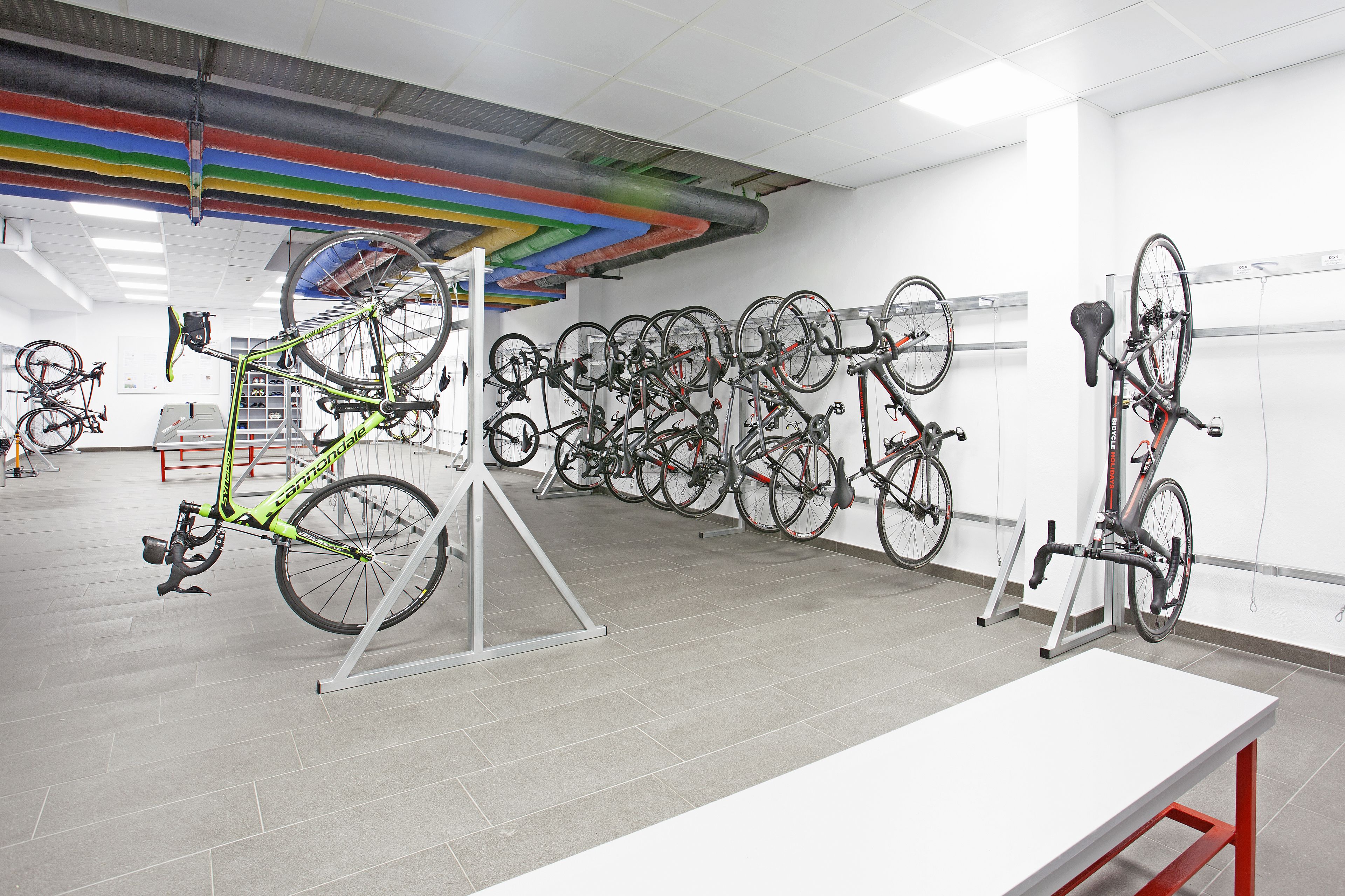A bicycle storage area with multiple bikes and a white table.