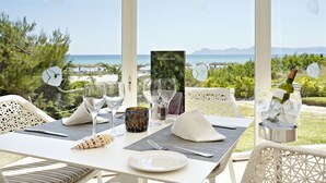 Una mesa dispuesta para cenar, con vistas al mar, un menú y una botella de champán.